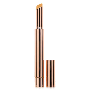 A tall thin rose gold tube frosted with the Kandi Koated logo containing a Finesse concealer stick in Ganache, its cap sitting beside it on a white background.